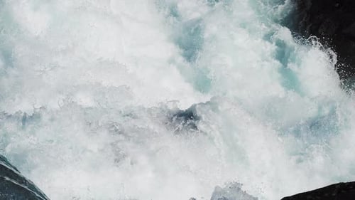 Close-up of a cascading waterfall, with whitewater tumbling and splashing over the dark rocky ledges