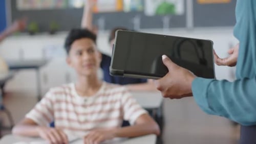 In school, boy raising hand in classroom, engaging with teacher