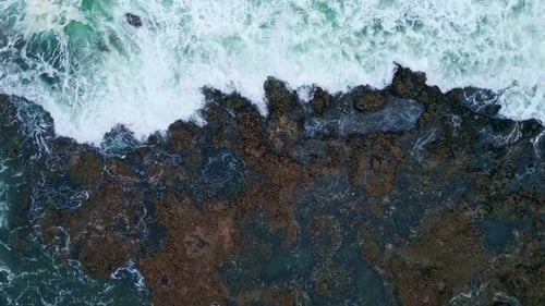 Dramatic stormy ocean waves crashing on volcanic cliffside in slow motion