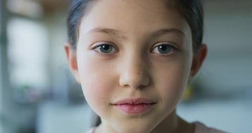 Close up portrait of a little girl with blue eyes looking in the camera on living room background.