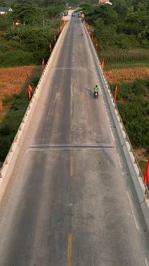 Des camions et des motos circulent sur le pont délabré qui traverse la rivière et la vallée à