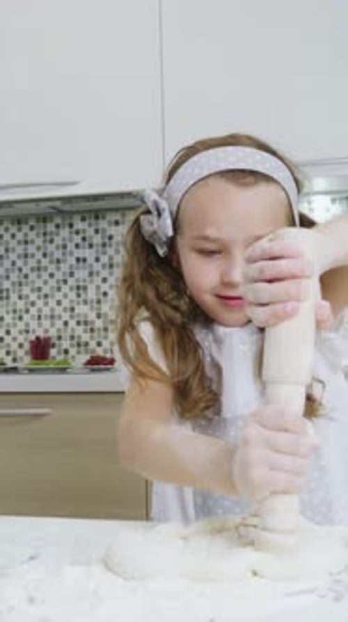 Jeune fille aux cheveux bruns roulant la pâte dans une cuisine lumineuse mettant en valeur ses compétences culinaires et