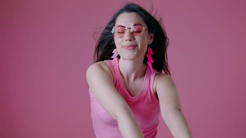 Woman Dancing in Pink Sunglasses Against Pink Background