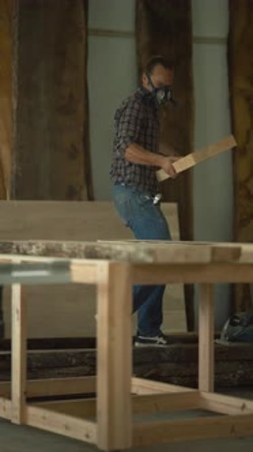Carpenter with Protective Mask Carrying Wooden Plank