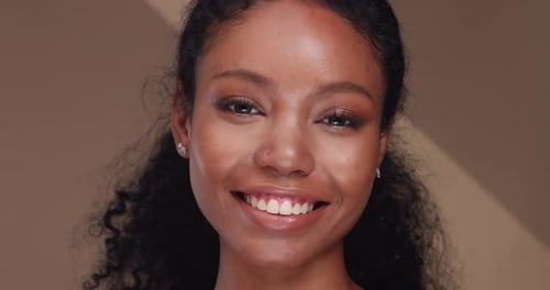 Portrait of a black girl with curly hair, soft makeup and perfect skin.