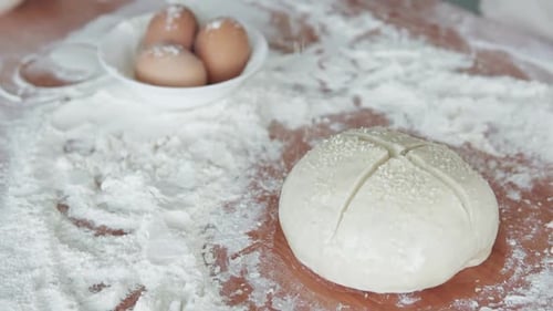 The cook sprinkles sesame seeds on the dough and begins to prepare crispy bread.