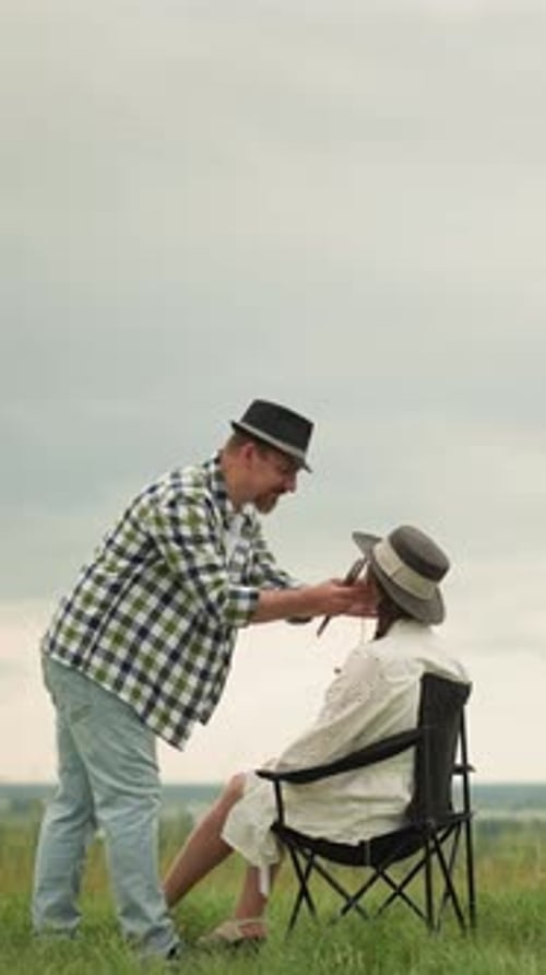 Illustrator Adjusts Woman's Hat in Serene Outdoor Setting