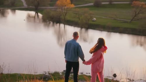 Romantic Couple Holding Hands at Sunset River View
