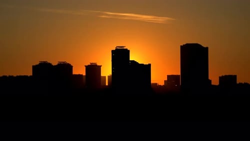 Silhouettes of high-rise buildings at sunset time lapse. Orange sunset in the cityscape.