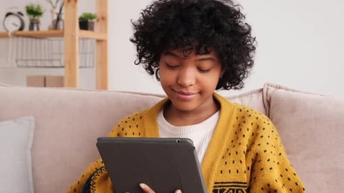 Woman Using Tablet Device Sitting Indoors on Couch