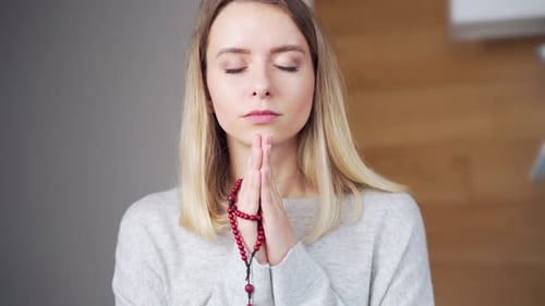 Woman Meditating with Prayer Beads in Quiet Room