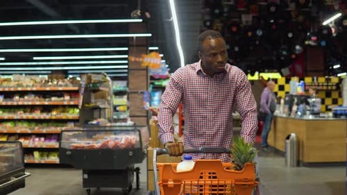 African American Man Walking with Shopping Trolley While Doing Shopping in Grocery Store