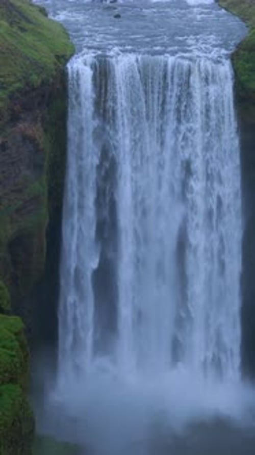 Dramatic CloseUp of a Lush Green Cliff with a Powerful Waterfall Cascading Down