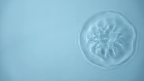 Natural Water Splashing Rings and Ripple Top View Clear Drop of Cosmetic Essence Serum Falling in