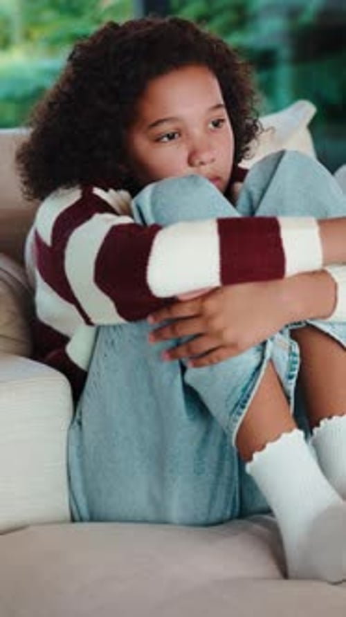 Thinking, sad and child on sofa in home with reflection for trauma, loneliness