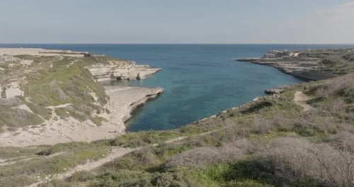 Aerial Drone shot over grass towards Kalanka Bay Malta