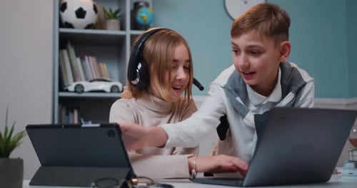Caucasian Boy and Girl Playing Game on Laptop and Tablet Device Together with Smile Face at home