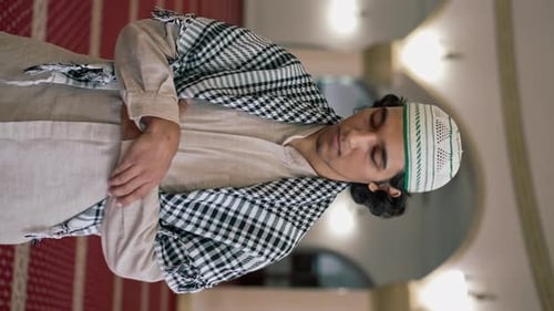Portrait en gros plan d'un homme arabe en costume national qui prie dans le hall de la mosquée avec ses yeux