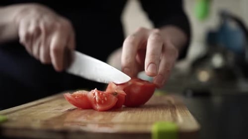 Adult Slicing a Tomato on a Cutting Board