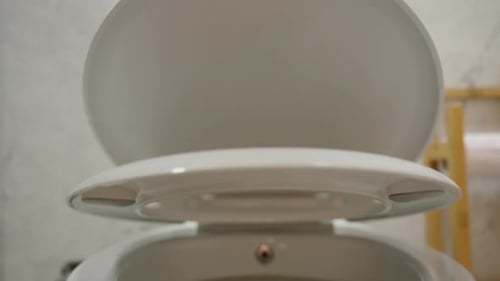 The camera watches from above as the toilet seat lids slowly and smoothly close. Close-up.