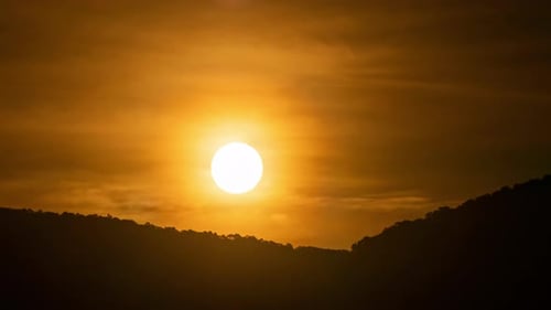 Zeitraffer eines dramatisch Sonnenaufgangs mit orangefarbenem Himmel an einem sonnigen Tag.