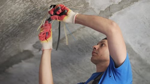 Man Repairing Electrical Wiring on a Ceiling