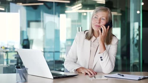 Mature Woman Working in Modern Office on Phone