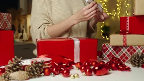 Person Wrapping Christmas Present with Silver Ribbon