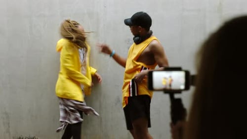 Energetic Dancers Performing in Front of Concrete Wall