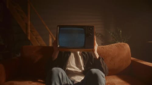 Figure Sits Holding Static TV on Couch
