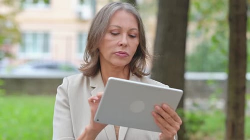 Portrait of Old Woman Using Tablet Outdoor