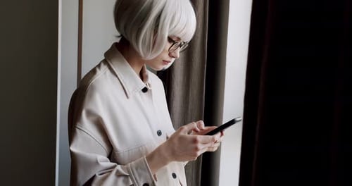 Woman with White Hair Using Smartphone Indoors