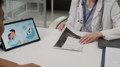 Femme remettant les résultats de l'échographie à un expert en FIV donnant un commentaire après les avoir regardés