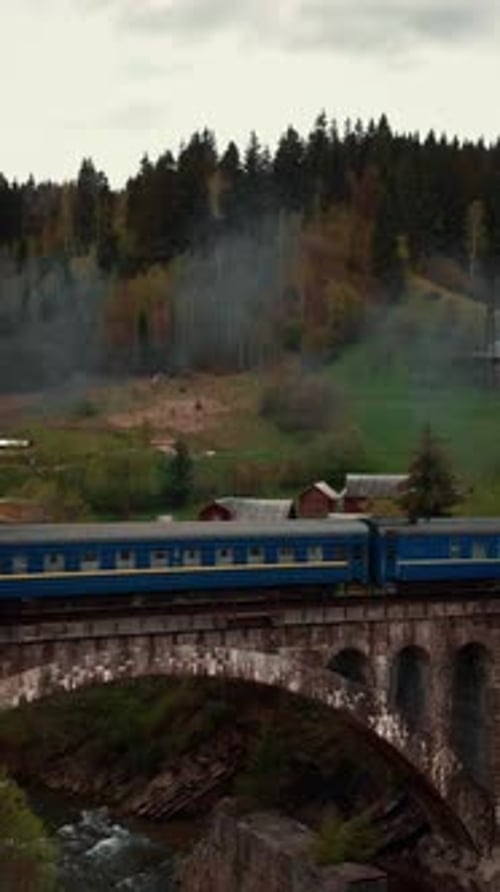 Passenger train passing over viaduct bridge in mountains. Vertical video