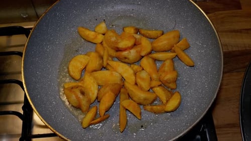 Potatoe quarters are being fryed in hot pan with hot and boiling oil on gas stove. Above shot of the