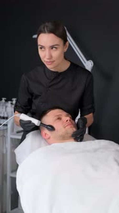 Woman Performing Facial Treatment on Man in Spa