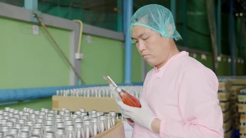 Un inspecteur vérifie les produits en bouteille sur la bande transporteuse d'une usine de boissons en maintenant une qualité élevée