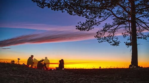 Timalpse d'un rassemblement autour d'un feu de camp sous un ciel nocturne animé