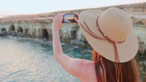 Overtheshould View of Young Attractive Happy Woman Standing Be the Seaside Taking Pictures of