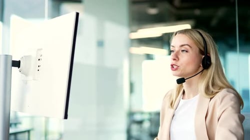 Side view. Woman in wireless headset customer service operator talking on video call using laptop