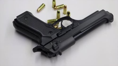 Verkleinern einer schwarzen Waffe mit scharfen 9-mm-Munitionsgeschossen auf einem weißen Tisch