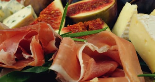 Figues, jamon, feuilles d'épinards et fromages bleus sur une planche de bois. Set de snacks.
