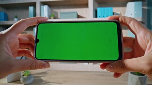 Mulher segurando o smartphone Chroma Key horizontal em closeup remoto do local de trabalho