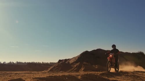 Long Shot of the Professional Motocross FMX Motorcycle Rider Drives Over the Dune and Further Down