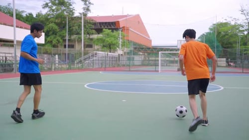 Asian two sportsman practicing football playing in the outdoors stadium.