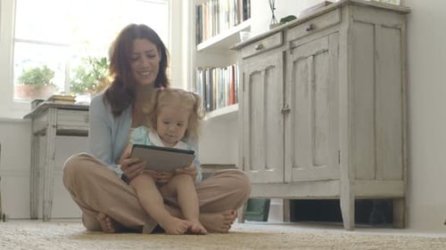Mother and daughter using tablet while sitting indoors