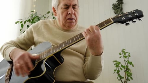 Senior Man Plays Acoustic Guitar in Home Setting