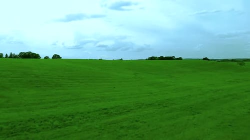 Aerial footage over green hill on village landscape