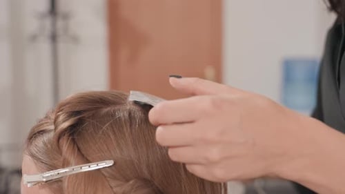 Woman getting hair highlighted at salon close up