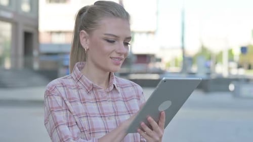 Young Woman Uses Tablet Outdoors in Urban Setting